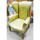 A Georgian style wing backed easy chair in green leather