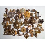 A collection of approximately 50 military cap badges, helmet plates,