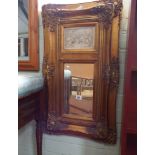 A mirror in an ornate gilt frame with plaster panel on top of young children