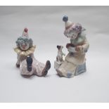 Two Lladro figures of child clowns, one playing accordion with a puppy, the other reclining.