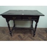 An Edwardian Arts and Crafts ebonised writing table with inset leather top and 2 drawers united by