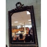 A decorative black and gilt over mantle mirror,