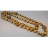 Row of antique ivory beads of uniform size, interspersed with carved beads.