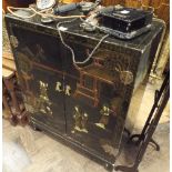 A Japanese black lacquer dwarf cabinet with a landscape scene picked out in relief to the doors