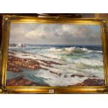 Oil on board painting of a coastline, indistinctly signed lower left, in a gilt frame.