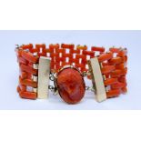 A coral bracelet of gate design with carved coral cameo inset to the oval clasp,