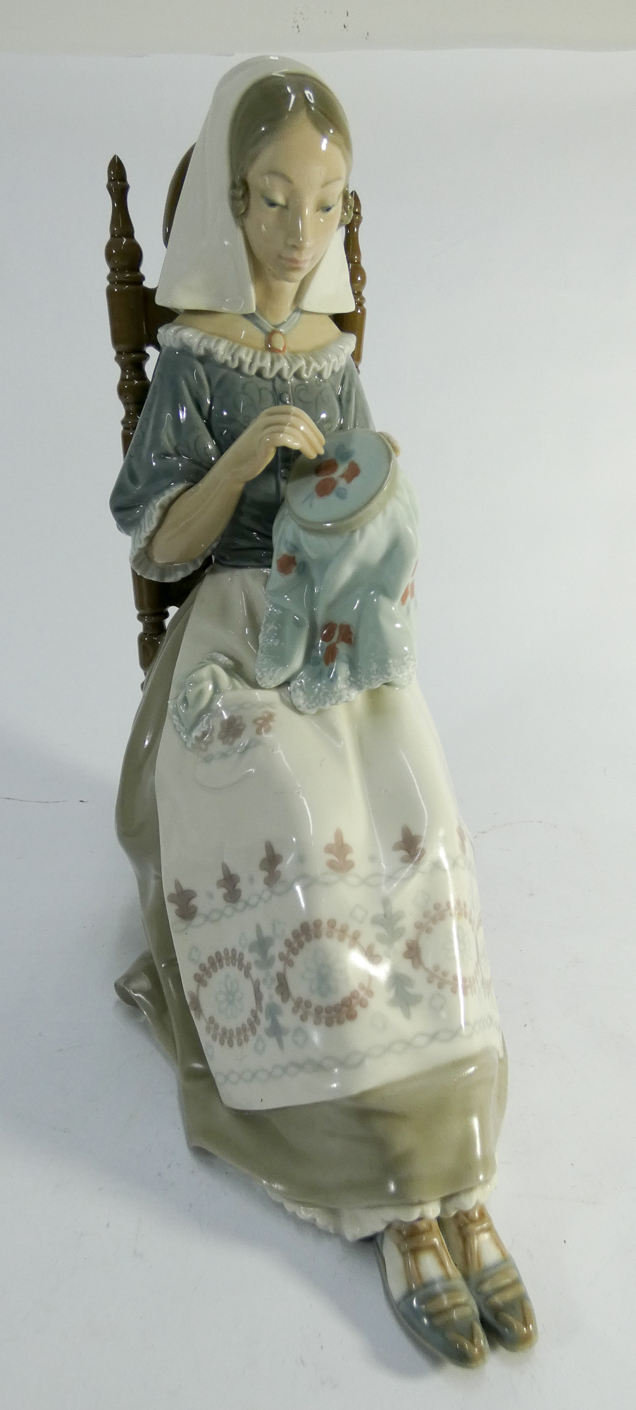 A large Lladro figurine of a seated lady sewing approx 30cms tall.