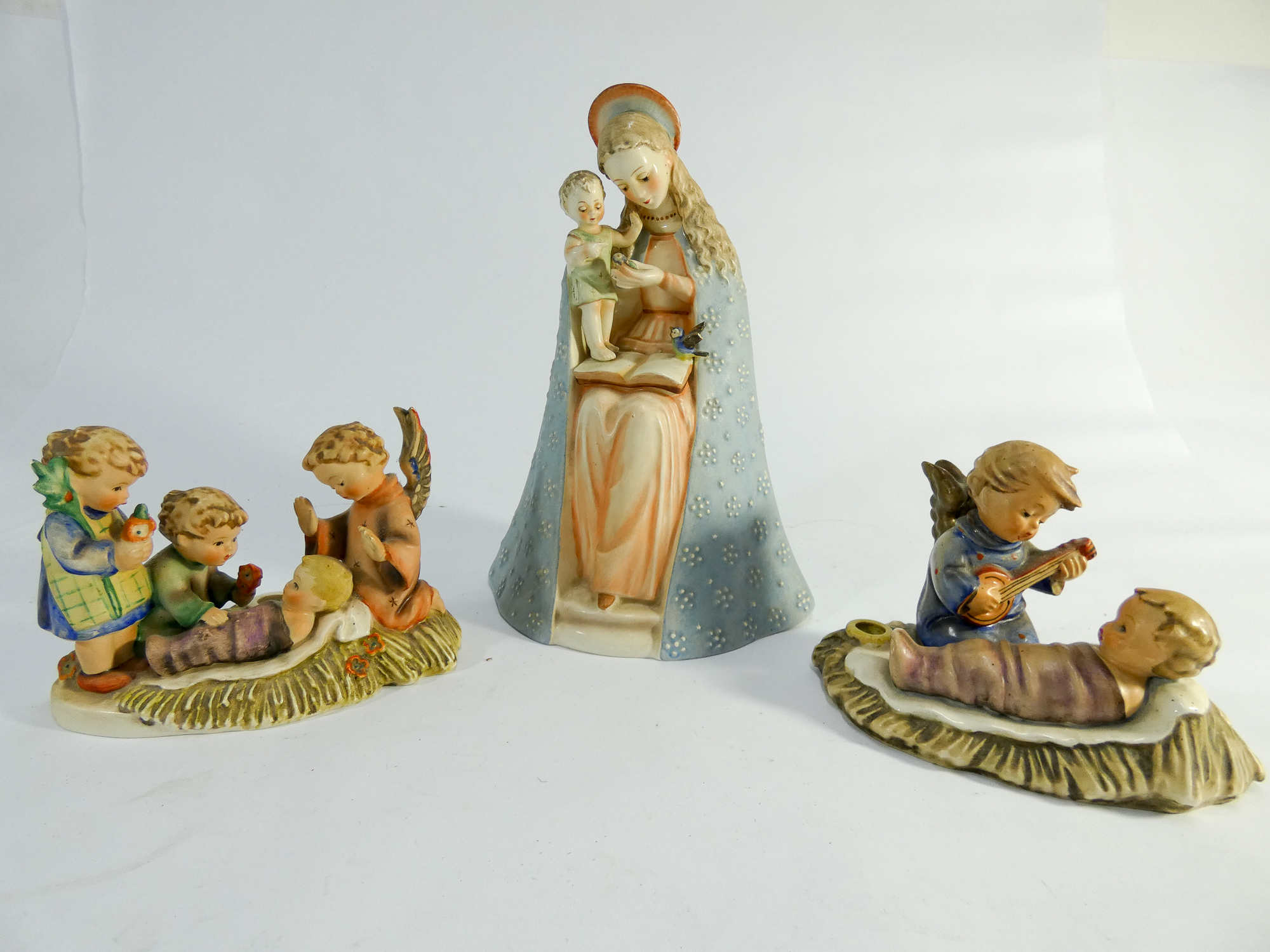 Three Hummel figurines of Virgin Mary and infant Jesus and two other nativity style scenes