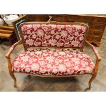 A French style walnut framed two seater settee upholstered in red and gold patterned brocade