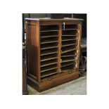 An early 20th century oak filing cabinet, the tambour front revealing two banks of shelves,