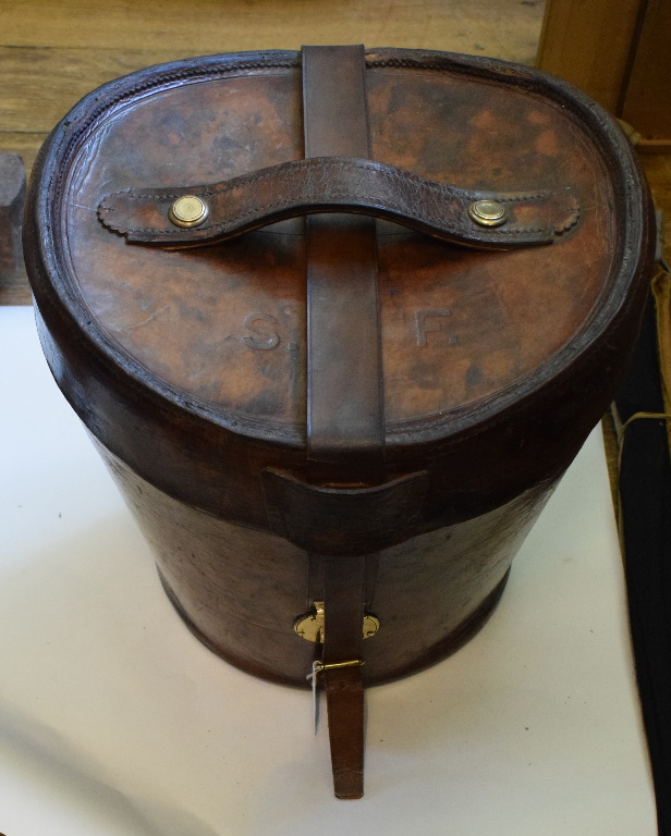 A late 19th/early 20th century leather top hat box, with brass fittings and purple quilted interior,