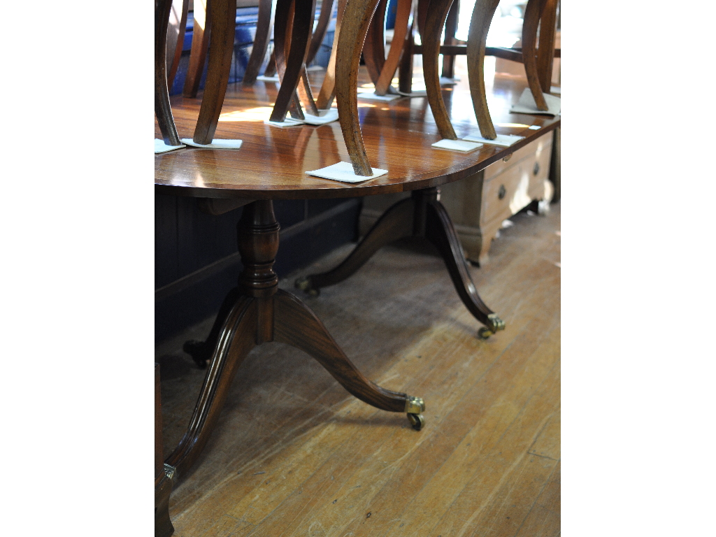 A Regency style inlaid mahogany twin pillar dining table, inset an extra leaf,