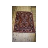 A Persian rug, decorated shapes on a red ground, within a multi border,