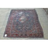 A Persian rug, decorated floral motifs on a red ground,
