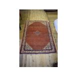 A Persian rug, decorated motifs on a pink ground,