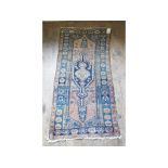A Persian rug, decorated geometric motifs on a blue ground,