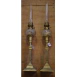 A pair of brass candlestick lamps, with cut glass reservoirs,