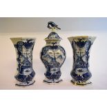 A garniture of three Dutch Delft vases, decorated buildings, some restoration,