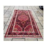 A Persian rug, with stylised motifs on a red ground, within a multi border,