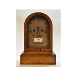 A mantel clock, the silver arched dial with Roman numerals, striking on a bell, in a maple case, 24.