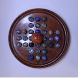 A collection of coloured glass marbles, on a treen solitaire board, 25 cm diameter,