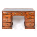 A late Victorian walnut kneehole desk, the leather inset top above an arrangement of nine drawers,