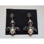 A pair of silver coloured metal drop earrings, in the form of bees,