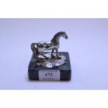 A desk weight, in the form of a silver horse mounted on a marble stand,