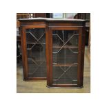 A pair of reproduction mahogany glazed corner cabinets,