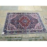 An Eastern rug, decorated a central medallion on a pink ground, within a multi border,