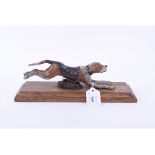 A painted metal dog paper clip, on a wooden plinth,