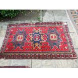 An Eastern rug, decorated three central lozenges on a red ground, within a multi border,