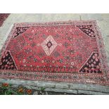 A Persian rug, decorated a central lozenge and motifs on a red ground, within a multi border,