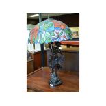 A bronzed figural table lamp, with a Tiffany style glass shade,