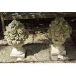 A pair of classical style reconstituted stone garden urns, spilling fruit and flowers,