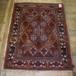 A Persian rug, decorated shapes on a red ground, within a multi border,