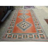 A Turkish carpet, decorated three central lozenges on a light red ground, within a multi border,