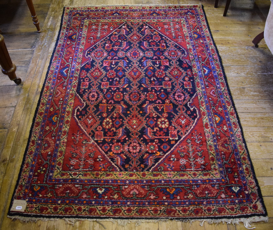 A Persian rug, decorated a central medallion on a red ground, within a multi border,