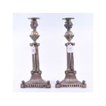 A pair of plated candlesticks, on triple column supports,