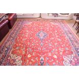 A Persian carpet, with central medallion and stylised floral motifs on a red ground,