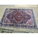 An Eastern rug, decorated a central medallion on a pink ground, within a multi border,