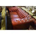 A red leather upholstered three seater settee