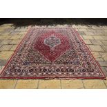 A Persian carpet, the central medallion and stylised geometric motifs on a red ground,