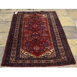 A Persian rug, with stylised floral motifs on a red ground, on a multi border,