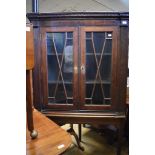 A George III inlaid oak corner cupboard, on a later stand,