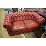 A red leather upholstered two seater settee