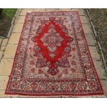 A Persian medallion carpet, with floral motifs on a red ground, within a multi border,