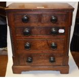 A 19th century oak miniature chest of two short and three long graduated drawers,