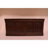 A Gothic carved oak collector's cabinet, the panel doors revealing a bank of drawers,