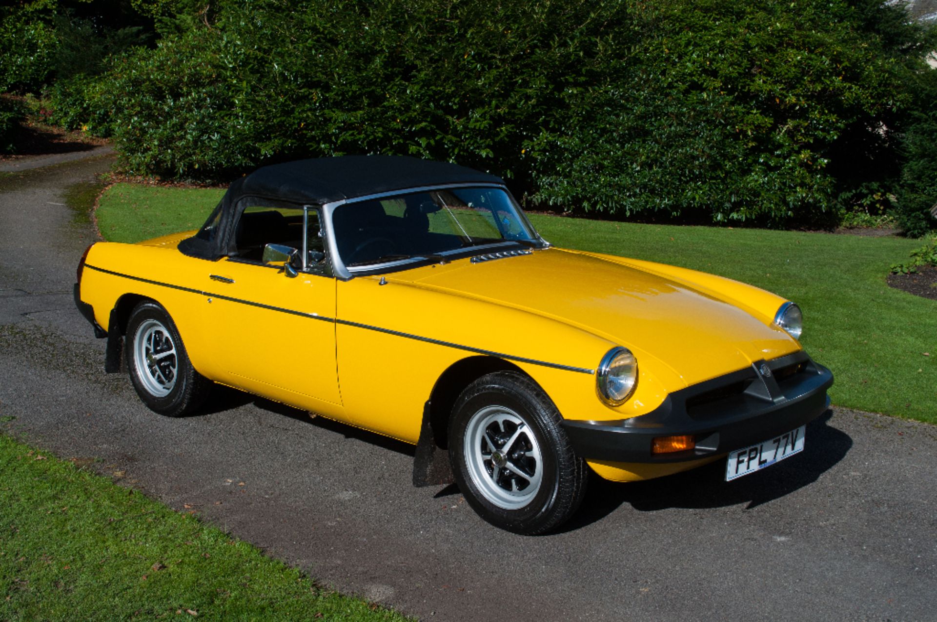 A 1980 MG B roadster, registration number FPL 77V, yellow.